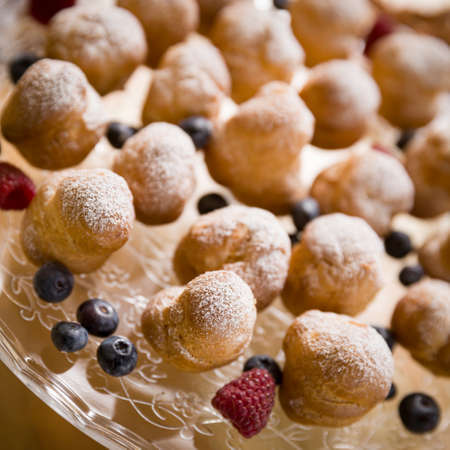 Top view on delicious profiteroles with vanilla cream and icing sugar. Profiteroles are decorated...