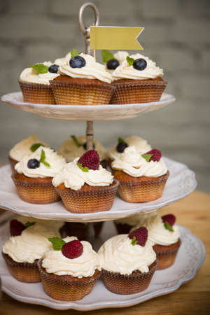 Delicious cupcakes stand on a multi-story stand with a flag at the very top. Healthy food for the...