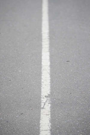 White continuous line on asphalt. Road marking on the highway. Selective focus of the line...