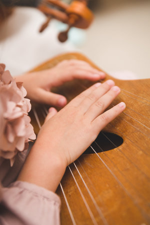 Closeup of a little girls hand playing an ancient musical instrument - gusli. Ancient folk plucked...