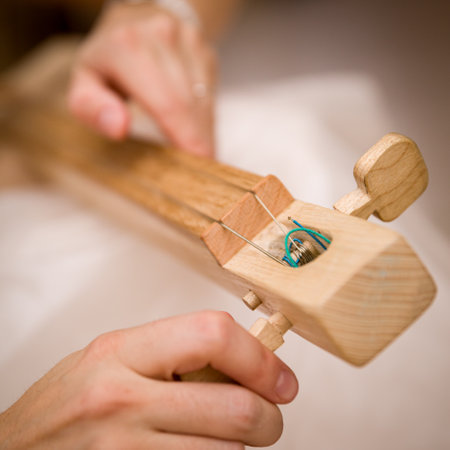 Closeup of female hands tuning a handmade wooden domra. The musician is preparing for the concert....
