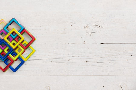 Closeup of plastic multi-colored constructor. Top view of childrens educational toys, magnetic figures, folded into a beautiful mosaic on a white wooden background.の写真素材
