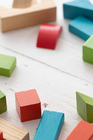 Closeup of colorful wooden toy blocks on white background wooden table. The child plays with colored...