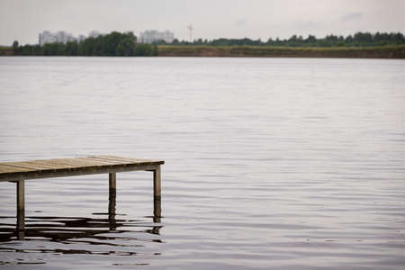 Empty wooden pier on a lake or river. A fisherman is getting ready to go to the fishing bridge....