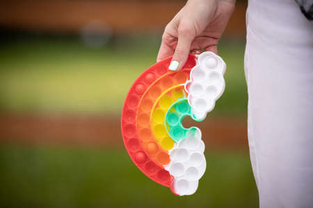 Woman holding rainbow bubble pop up fidget toy. For autistic patients to relieve stress and help...