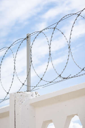 Closeup of concrete wall with barbed wire on background. The concept of prison, salvation, refugee