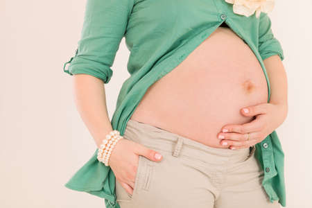 Young pregnant belly woman close-up in a green shirt, hugging her belly. We expect a child....