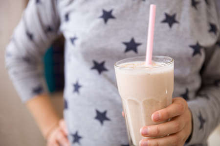 The girl holds in his hands a big glass with a dairy smoothie. fitness and healthy lifestyleの写真素材