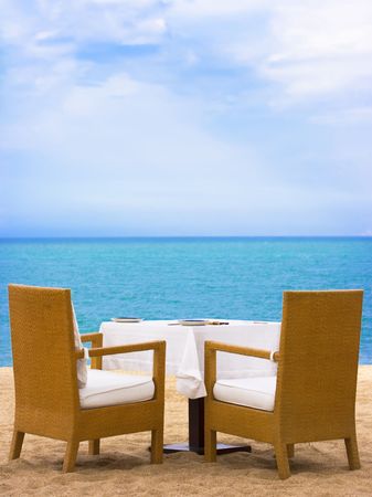 Dining table on white sand beach close to the oceanの写真素材