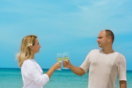 Young couple with glasses of white wine on the tropical beachの写真素材