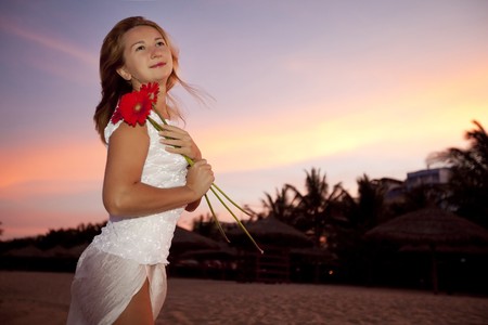 Young woman with gerbera flowers on sunset timeの写真素材