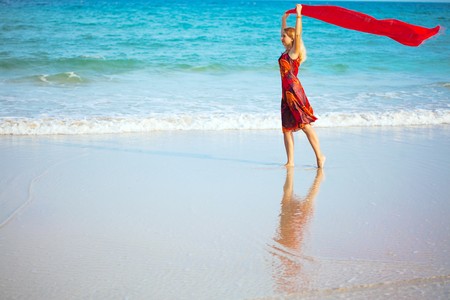 Beautiful woman walking near the ocean with red sarongの写真素材