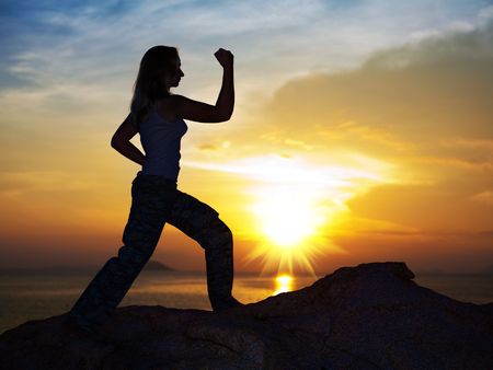 Silhouette of woman doin training exercise at sunrise timeの写真素材