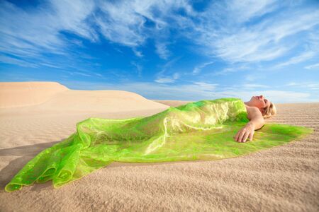 Beautiful woman sleeping in the middle of desertの写真素材