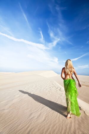 Woman walking in the middle of desertの写真素材