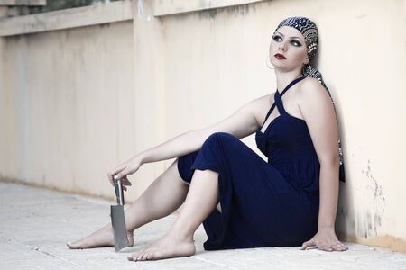 Woman with knife sitting on the streetの写真素材