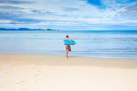Man with body board on the tropical beachの写真素材