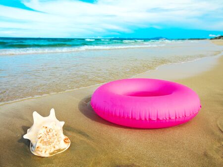 Seashell and inflatable tube on the beach