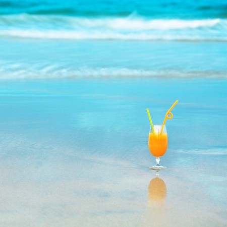 Glass of orange juice on the beachの写真素材