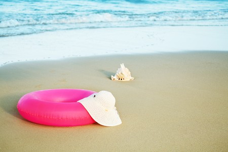 Seashell, inflatable tube and hat on sandの写真素材