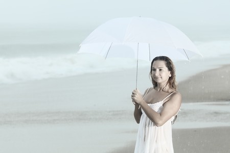Beautiful woman near the stormy ocean at rainの写真素材