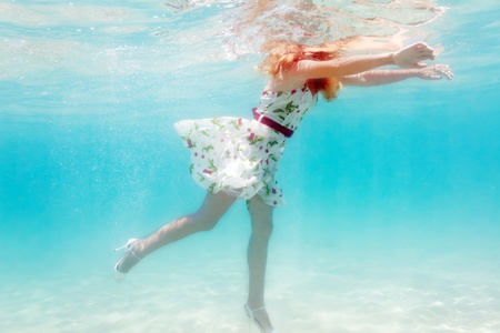 Young beautiful woman in white dress underwaterの写真素材