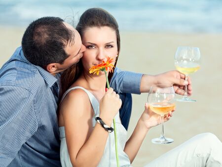 Young beautiful couple drinking wine on the beachの写真素材