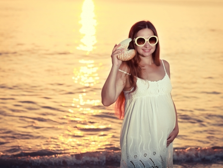 Beautiful pregnant woman at sunrise near the seaの写真素材