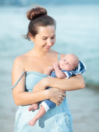 Young mother with baby on the beachの写真素材