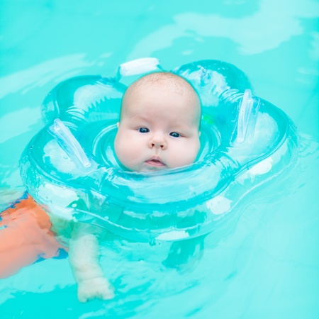 Baby swimming with neck swim ring in poolの写真素材