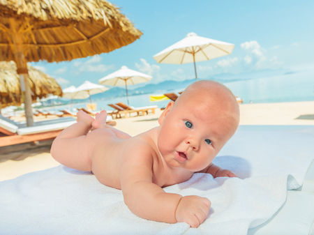 Cure baby laying on the sunbed at the beachの写真素材
