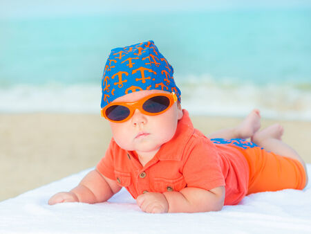 Cute baby laying on the sunbed at the beachの写真素材