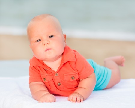 Cute baby laying on the sunbed at the beachの写真素材