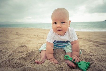 Cute baby sitting on a sand の写真素材