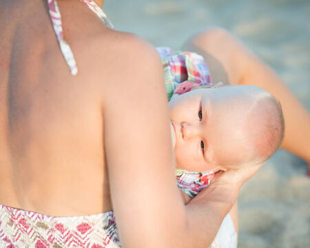 Mother breastfeeding baby on the beachの写真素材