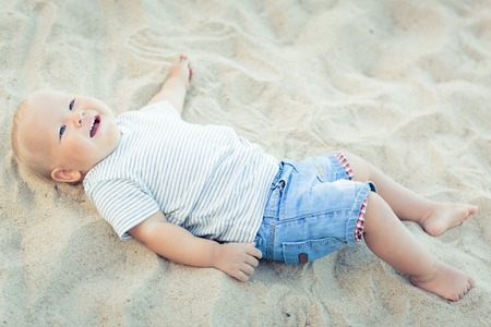 Cute baby lying down on a sand