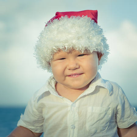 Little Santa boy on the beach.の写真素材