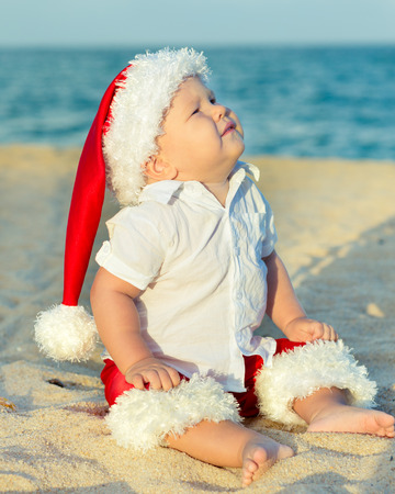 Little Santa boy on the beach.の写真素材