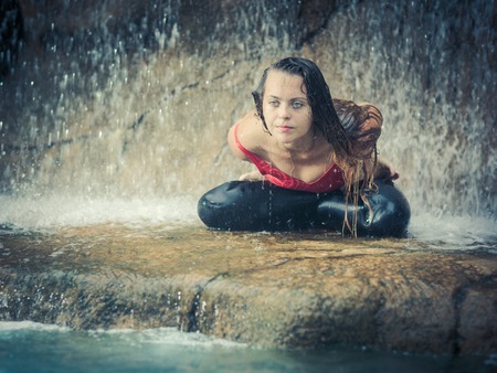 Woman practicing yoga near waterfall. Lotus Pose. Baddha Padmasanaの写真素材