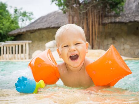 Baby with armbands in swimming poolの写真素材