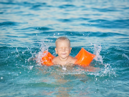 Baby with armbands in a seaの写真素材