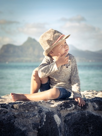 Child  looking into the distance on the beach at sunset timeの写真素材