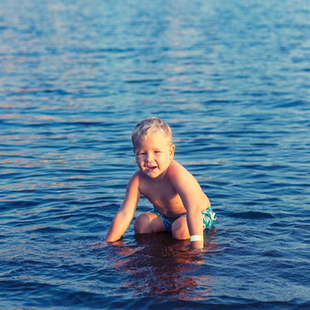 Cute boy plays in a seaの写真素材