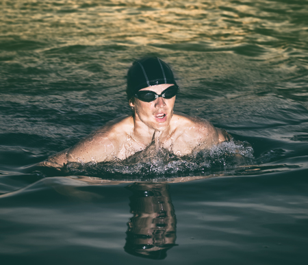 Swimmer breathing during swimming crawl in the sea at sunsetの写真素材