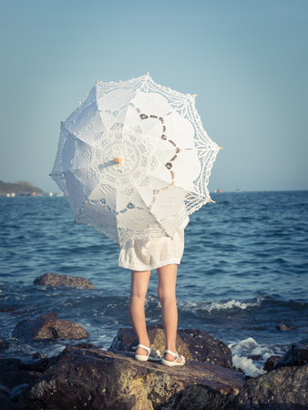 Little girl with umbrella near the seaの写真素材