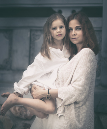 Beautiful portrait of a mother holding daughter outdoorの写真素材