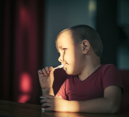 Portrait of a boy eating ice cream. High contrast hard light portrait