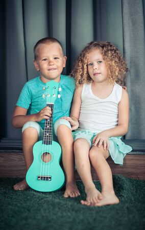 Portrait of a cute kids sitting ouddoor with ukuleleの写真素材