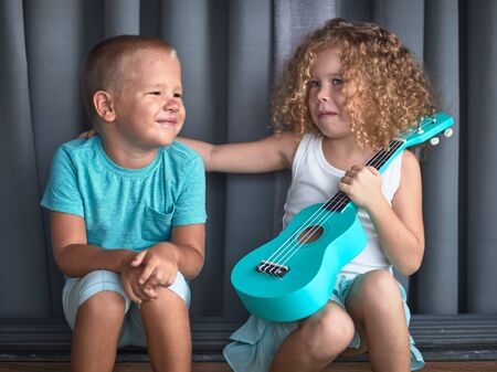 Portrait of a cute kids sitting ouddoor with ukuleleの写真素材