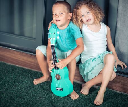 Portrait of a cute kids sitting ouddoor with ukuleleの写真素材